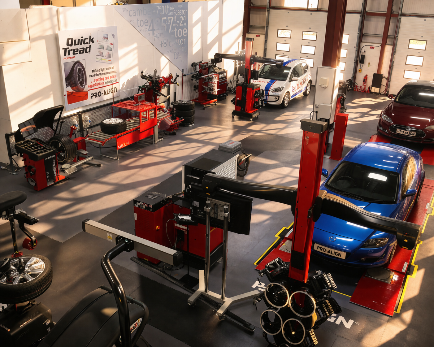 Wide view of a professional wheel alignment workshop with multiple vehicles on alignment racks and diagnostic equipment